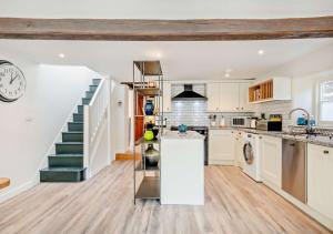 a kitchen with a staircase and a kitchen with white cabinets at Old Flint Bank Cottage in Harleston