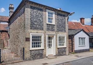 una vecchia casa in mattoni con porte e finestre bianche di Old Flint Bank Cottage a Harleston