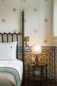 ein Schlafzimmer mit einem Bett und einem Tisch mit einer Lampe in der Unterkunft Vermelho Melides in Melides