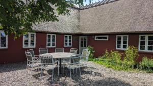 a table and chairs in front of a red building at Under Valnødden in Stubbekøbing