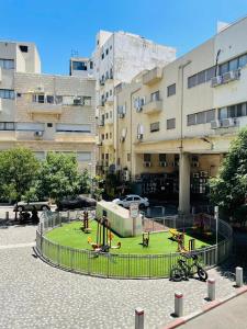 une aire de jeux dans un parc en face d'un bâtiment dans l'établissement Haneemanim Apartments, à Haïfa