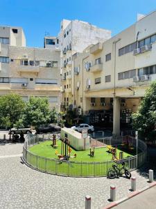 un patio de juegos en un parque frente a un edificio en Haneemanim Apartments, en Haifa