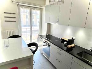a kitchen with white cabinets and a black counter top at CH Apartment Lausanne Gare in Lausanne