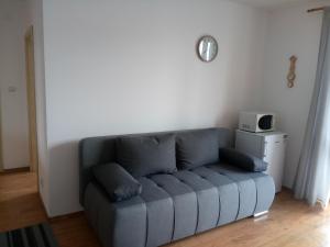 a blue couch in a living room with a clock on the wall at Apartmány Liptov in Liptovský Mikuláš