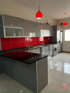 a kitchen with red and gray cabinets and a stove at Hellen Apartament in Praia