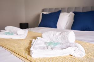 2 toallas blancas encima de 2 camas en West Apartment en Coatbridge