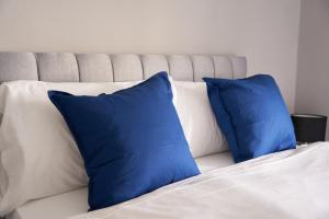 two blue pillows sitting on a white bed at West Apartment in Coatbridge
