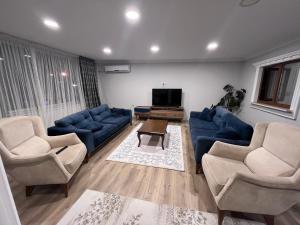 ein Wohnzimmer mit blauen Sofas und einem TV in der Unterkunft Bayraktar apart in Pelitli