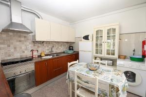 una cucina con armadi bianchi e tavolo con sedie di Akisol Apartments in Burgau a Budens