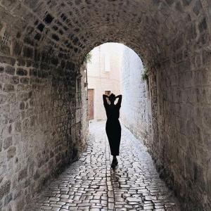 Una mujer con un vestido negro caminando por un túnel en Split Apartments Beta, en Split