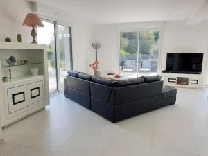 a living room with a black couch and a television at Maison moderne au cœur du Golfe du Morbihan ! in Plougoumelen