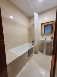 a bathroom with a bath tub and a sink at Apartamento PUERTO in Mazagón +11 photos
