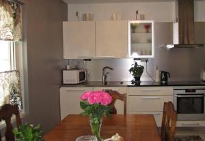 una cocina con una mesa con un jarrón de flores rosas en Lovely apartment in the heart of Naantali en Naantali
