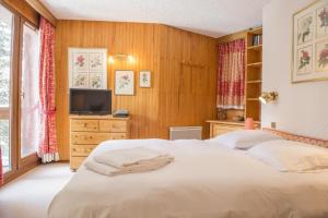 a bedroom with a white bed and a television at Luxury apartment near the slopes in Courchevel in Courchevel