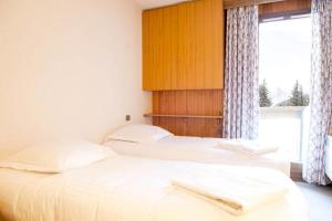 two twin beds in a room with a window at Luxury apartment near the slopes in Courchevel in Courchevel
