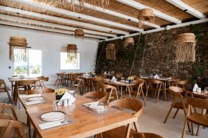 a restaurant with wooden tables and chairs and a brick wall at Super Paradise Hotel in Super Paradise Beach