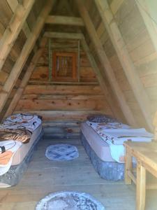 two beds in a log cabin with a table at Mountain cottage Captain's Lake, Kapetanovo jezero in Kolašin