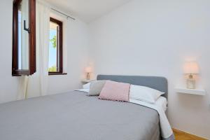a white bedroom with a bed with a pink pillow at Sunset Oasis in Dubrovnik