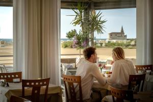 un hombre y una mujer sentados en una mesa en un restaurante en Hotel Delfino, en Caorle