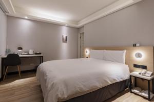 a bedroom with a large white bed and a desk at Hubhotel Benqiao Inn Far Eastern Branch in Taipei
