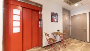 een rode deur in een kamer met een tafel en stoelen bij FLY CAT HOTEL in Minokamo
