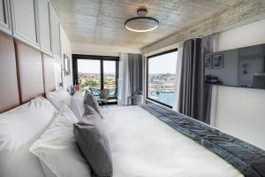 a living room with a white couch and large windows at The Londoner Hotel Sliema in Sliema