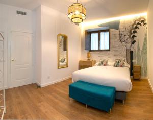 a bedroom with a large white bed and a blue stool at GALIANA CERVANTES 5 COLLECTION in Toledo