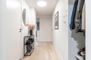 a hallway with white walls and wood floors and a mirror at Brand new in Bergen