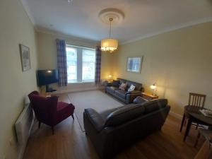 a living room with a couch and a chair at Stunning Village Centre Holiday Home in Callander