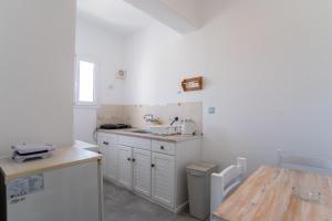 a kitchen with white cabinets and a sink and a table at Livadia Seaside Studios 7 in Parikia