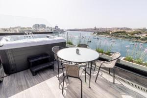 un balcon avec une baignoire, des tables et des chaises dans l'établissement The Londoner Hotel Sliema, à Sliema
