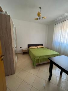 a bedroom with a green bed and a table at Laert's Home in Sarandë