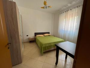 a small bedroom with a green bed and a table at Laert's Home in Sarandë +2 photos