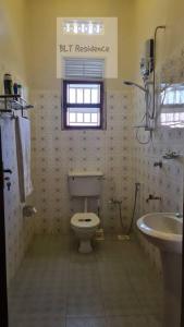 a bathroom with a toilet and a sink and a window at BLT Residence - Kasese A serene and tranquil home in Kasese