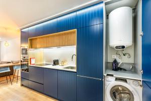 Sé Apartamentos - Dom Miguel Apartment في براغا: مطبخ مع دواليب زرقاء وغسالة ملابس