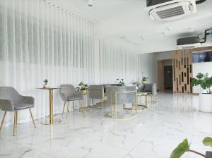 a room with tables and chairs and a wall at Golden Nest Hotel Suvarnabhumi in Bangkok