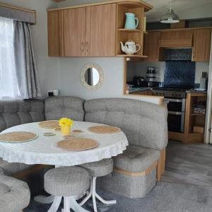 a living room with a table and chairs and a kitchen at Pet friendly family caravan with secure private garden in Patrington