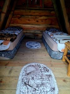 two beds in a log cabin with two rugs at Mountain cottage Captain's Lake, Kapetanovo jezero in Kolašin
