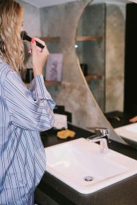 SOULSISTERS' Hotel في كابرون: امرأة تنظف أسنانها أمام المرآة