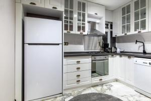a kitchen with white cabinets and a refrigerator at Comfy and Central Flat in the Heart of Sisli in Istanbul