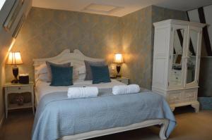 a bedroom with a large bed with blue pillows at Le Bouchon Brasserie & Hotel in Maldon