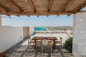 einen Holztisch und Stühle auf einer Terrasse mit Strand in der Unterkunft Villa Mousa in Mikri Vigla