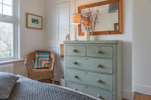 a bedroom with a dresser with a mirror and a chair at Poppy Cottage in Kingsdown