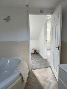 a bathroom with a tub and an open door at El Sea House in Chapel Saint Leonards