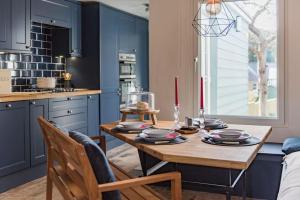 a kitchen with a wooden table and blue cabinets at Poppy Cottage in Kingsdown