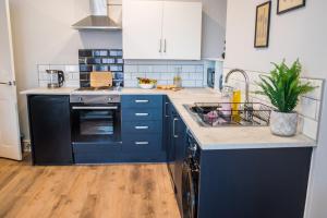 a kitchen with blue cabinets and a sink at Blackpool Abode - Beach Suite Apartment in Blackpool