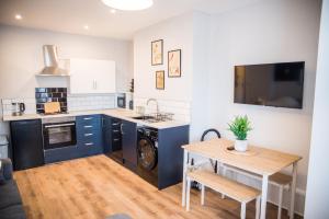 a kitchen with blue cabinets and a wooden table at Blackpool Abode - Beach Suite Apartment in Blackpool