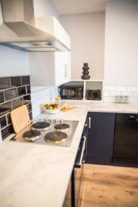 a kitchen with a stove and a bowl of fruit on the counter at Blackpool Abode - Beach Suite Apartment in Blackpool