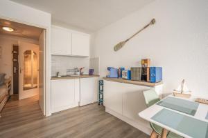 Una cocina con gabinetes blancos y una mesa. en L'Escale de la Plage, en Gruissan