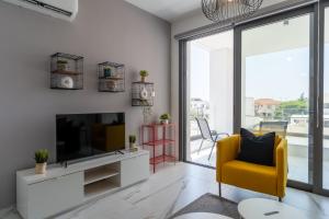 a living room with a tv and a yellow chair at Yasou 1- Bedroom Apartment in Larnaca in Larnaca